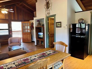 Una sala acogedora con una mesa de madera, televisor y refrigerador.