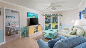 A living room with a TV, a sofa, a coffee table, and a view of the outside.