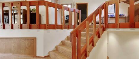 A multi-level home interior with a wooden staircase and a view of the living area.