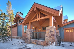 A lodge with a stone entrance, wooden beams, and a snow-covered ground.