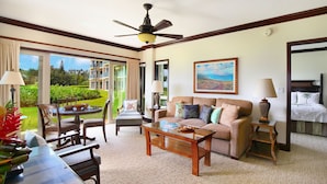 A hotel room with a large window, a ceiling fan, a sofa, a coffee table, and a bed. - Waipouli Beach Resort Exquisite Ocean Front Condo in Oceanfront "H" Building (Kapaa)