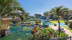A resort with multiple swimming pools, palm trees, and a clear blue sky. - Waipouli Beach Resort Exquisite Ocean Front Condo in Oceanfront "H" Building (Kapaa)