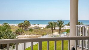 A balcony with a view of the beach, palm trees, and a clear sky. - Escape to Paradise on Treasure Island (Treasure Island)