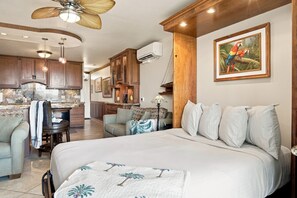A spacious living area with a large bed, a dining table, and a kitchen in the background.