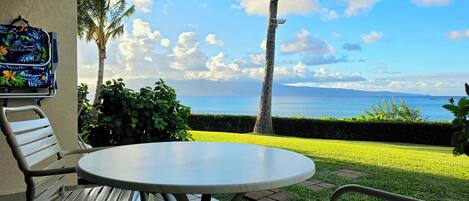 An outdoor patio with a table and chairs, a hanging bag, and a view of the sea.