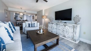 A living room with a sofa, coffee table, and a TV mounted on the wall. - D506 Corner unit, 2 balconies, Fantastic view of Pool and Gulf (Panama City Beach)