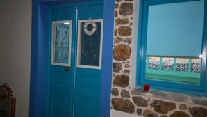 Una habitación con dos puertas azules, un muro de piedra y un ventanal con vistas.