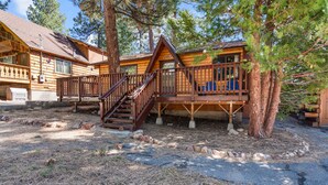 Eine Holzhütte mit einer Terrasse und Treppe, umgeben von Bäumen.