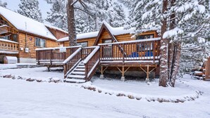 A wooden cabin with a covered deck and stairs leading to a porch.
