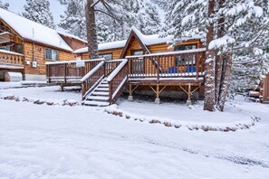 A wooden cabin with a covered deck and stairs leading to a porch.