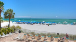 Una playa con tumbonas y sombrillas, un cielo azul despejado y el océano al fondo.