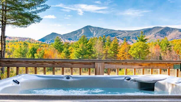 A hot tub with a wooden deck and a view of mountains and autumn foliage. - Mountain Home, Views, Near Whiteface, Lake Placid (Wilmington)