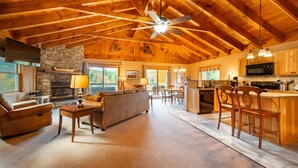 A spacious living area with a fireplace, a sofa, and a dining area with wooden chairs. - Mountain Home, Views, Near Whiteface, Lake Placid (Wilmington)