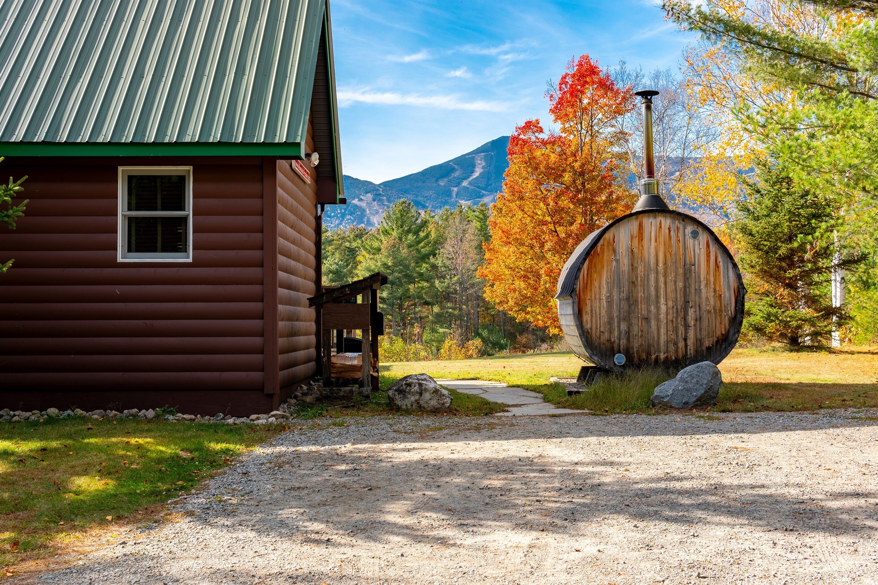 Un chalet rustique avec un tonneau en bois et une vue sur la montagne.