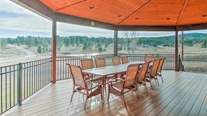 Une terrasse extérieure couverte, avec une table et des chaises en bois, donnant sur un paysage pittoresque.