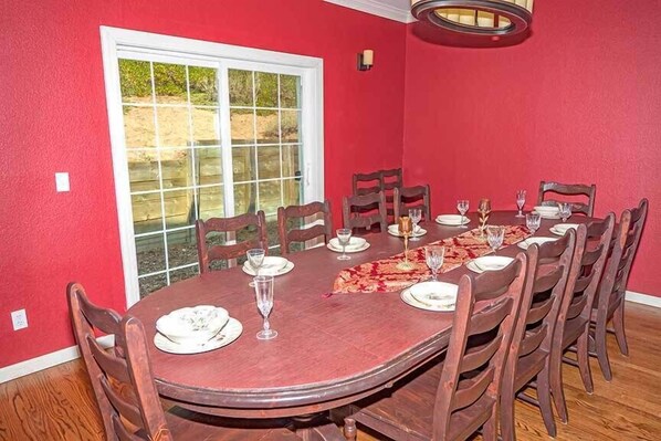 A dining room with a round table set for six, surrounded by wooden chairs.