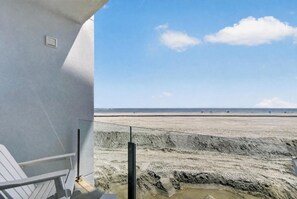 A beach view from a balcony with a clear sky.