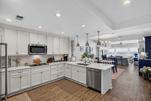 A modern kitchen with white cabinetry, stainless appliances, and pendant lighting.