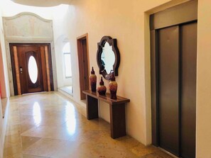 A hallway with a wooden door, a bench with vases, and a wall-mounted mirror.