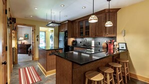 A modern kitchen with wooden cabinets, a black countertop island, and bar stools.