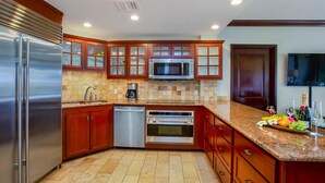 Una cocina moderna con electrodomésticos de acero inoxidable, armarios de madera y encimera de granito.