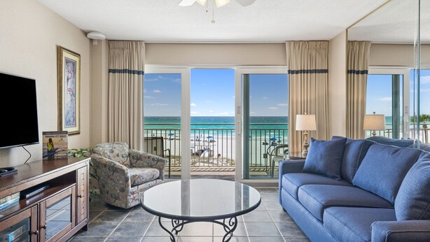 A hotel room with a balcony, a television, a sofa, a coffee table, and a framed picture on the wall.