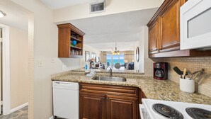 A kitchen with granite countertops, wooden cabinets, a dishwasher, and a stove.