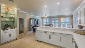 A spacious kitchen with white cabinetry, a large island, and a view to the outside. - Drift Woods. Unforgettable Family Retreat – Gulf-Front Townhome on Navarre Beach (Navarre Beach)