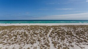 A beach with white sand and sparse vegetation, leading to the ocean. - Drift Woods. Unforgettable Family Retreat – Gulf-Front Townhome on Navarre Beach (Navarre Beach)