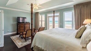 A bedroom with a large bed, a ceiling fan, a dresser, a TV, and a view of the ocean. - Drift Woods. Unforgettable Family Retreat – Gulf-Front Townhome on Navarre Beach (Navarre Beach)