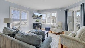 A living room with a sofa, armchairs, a coffee table, and a TV. - 304 E Port by AvantStay | Rooftop Deck | Incredible Ocean & Beach Views! (Isle Of Palms)