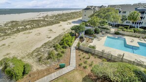 A beachfront property with a swimming pool, a wooden deck, and a view of the beach and ocean. - 304 E Port by AvantStay | Rooftop Deck | Incredible Ocean & Beach Views! (Isle Of Palms)