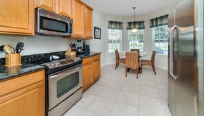 Kitchen with dining area, equipped with a stove, refrigerator, and microwave, and offering views of the outdoors.