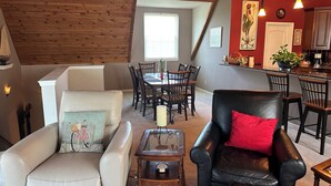 Ein gemütliches Wohnzimmer mit Essbereich, Holzboden und einer Küche im Hintergrund.