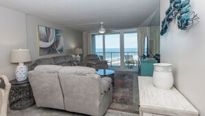 Een woonkamer met een bank, fauteuils, een salontafel en uitzicht op de oceaan.