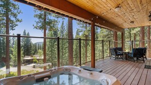 Eine Holzterrasse mit Whirlpool und Sitzgelegenheiten im Freien.
