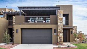 A modern two-story house with a large garage, stone accents, and a covered patio. - Stunning Red Rock Views - 4BR Poolside Fire Pit (St. George)
