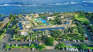 Vista aérea de un resort con piscina, paneles solares y vistas al océano.