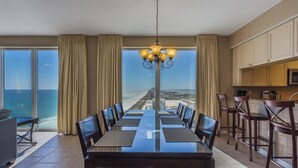 Un espace repas avec vue sur la plage, un lustre et un coin cuisine.