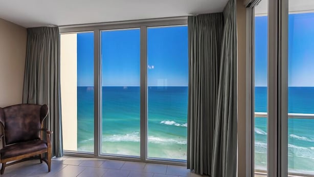 Une pièce dotée d’une grande porte-fenêtre coulissante donnant sur un balcon avec vue sur l’océan.