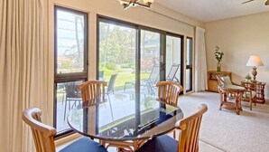 A dining area with a round glass table, wooden chairs, and a chandelier. - Peaceful Paradise! Spacious Condo, Full Kitchen, Wifi, Flat Screens-Kaha Lani 108 (LIHUE)
