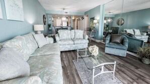 A spacious living room with a sectional sofa, a chaise lounge, and a glass coffee table.