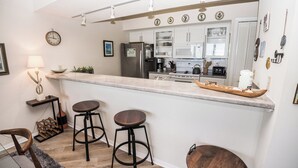 Una cocina moderna con una isla central, taburetes de bar y un refrigerador.