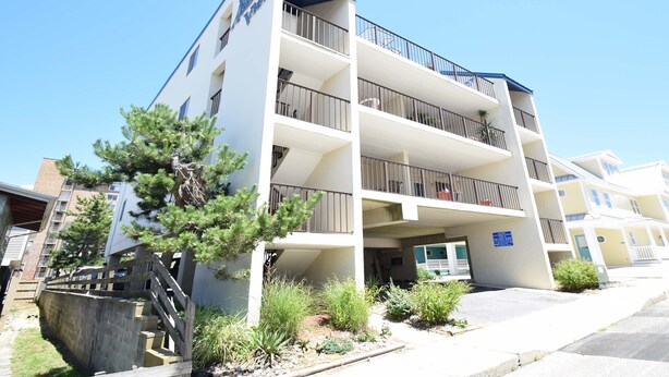 A multi-story hotel with balconies, a staircase, and a landscaped front yard. - Atlantic View 101-Oceanside 83rd St, Free WiFi, W/D, AC (Ocean City)