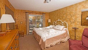 A bedroom with a bed, wooden dresser, and a chair.
