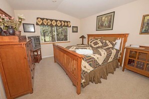 A bedroom with a wooden bed, a dresser, a TV, and a window with curtains.