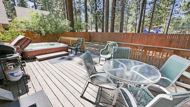 Une terrasse en bois avec un jacuzzi, un coin salon extérieur et un barbecue.