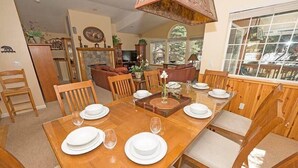Un coin repas avec une table en bois dressée pour six personnes, entourée de chaises en bois.