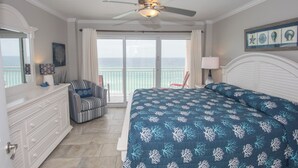 A bedroom with a bed, a chair, a dresser, a ceiling fan, and a view of the ocean. - D1005 Direct Gulf View, 3 Pools, Tennis and Pickle Ball (Panama City Beach)