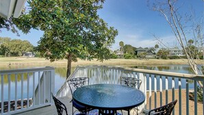 A deck with a table and chairs overlooking a body of water, surrounded by a white railing. - 15 Lake Village Lane by AvantStay | Golf Course & Lagoon Views (Isle Of Palms)